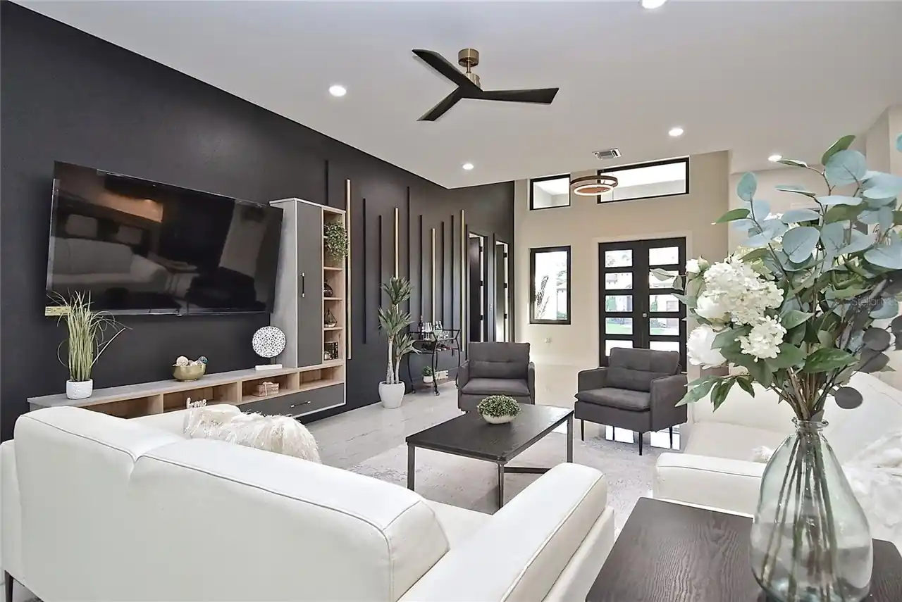 Living room with a black accent wall, mounted TV, and view toward the entry doors.