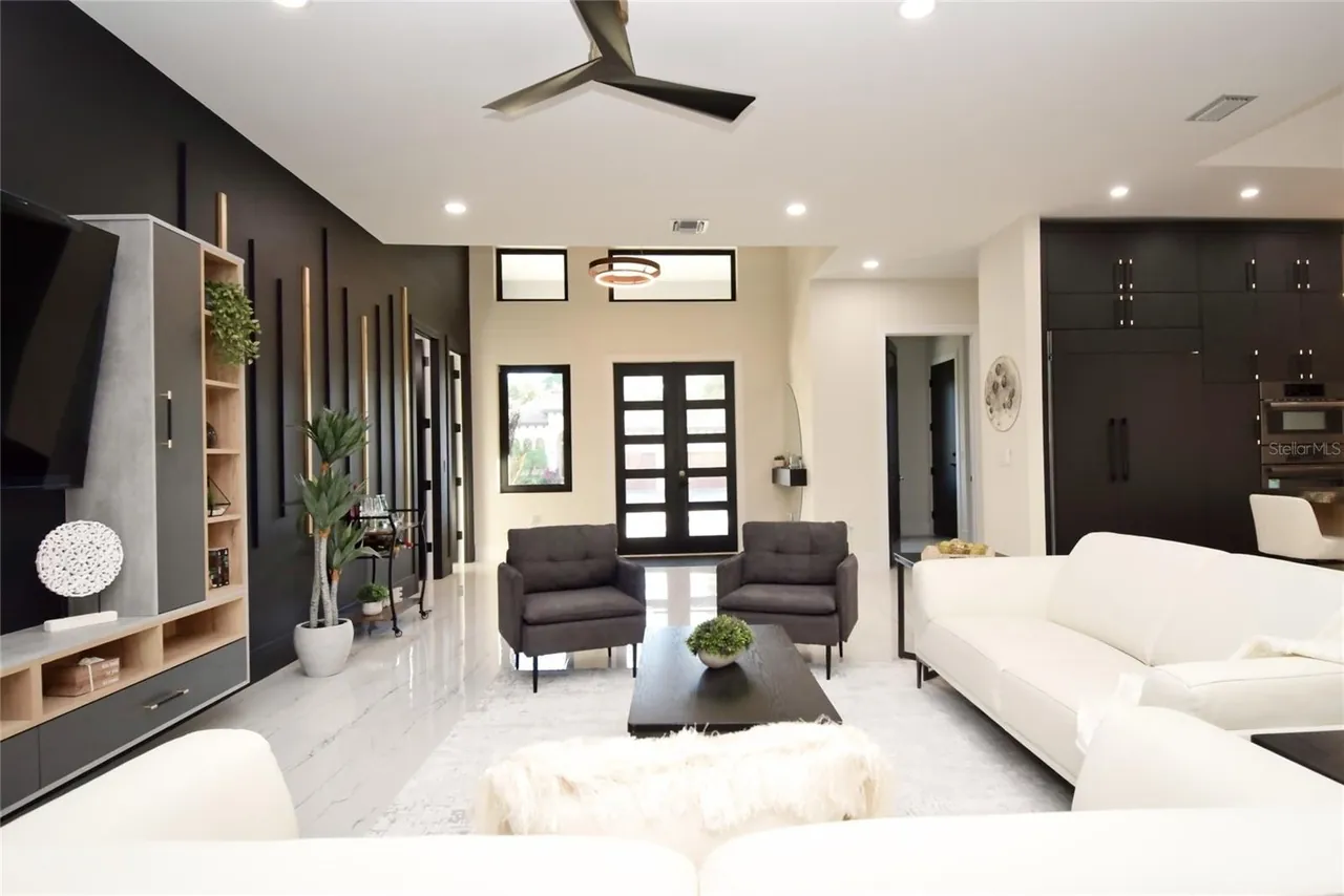 Living room seating arranged around open shelving and a media wall.