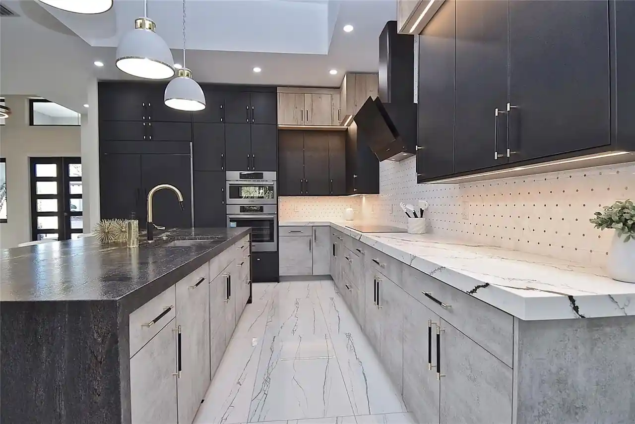 Galley-style kitchen with dark upper cabinets, a waterfall island, and a built-in wall oven.