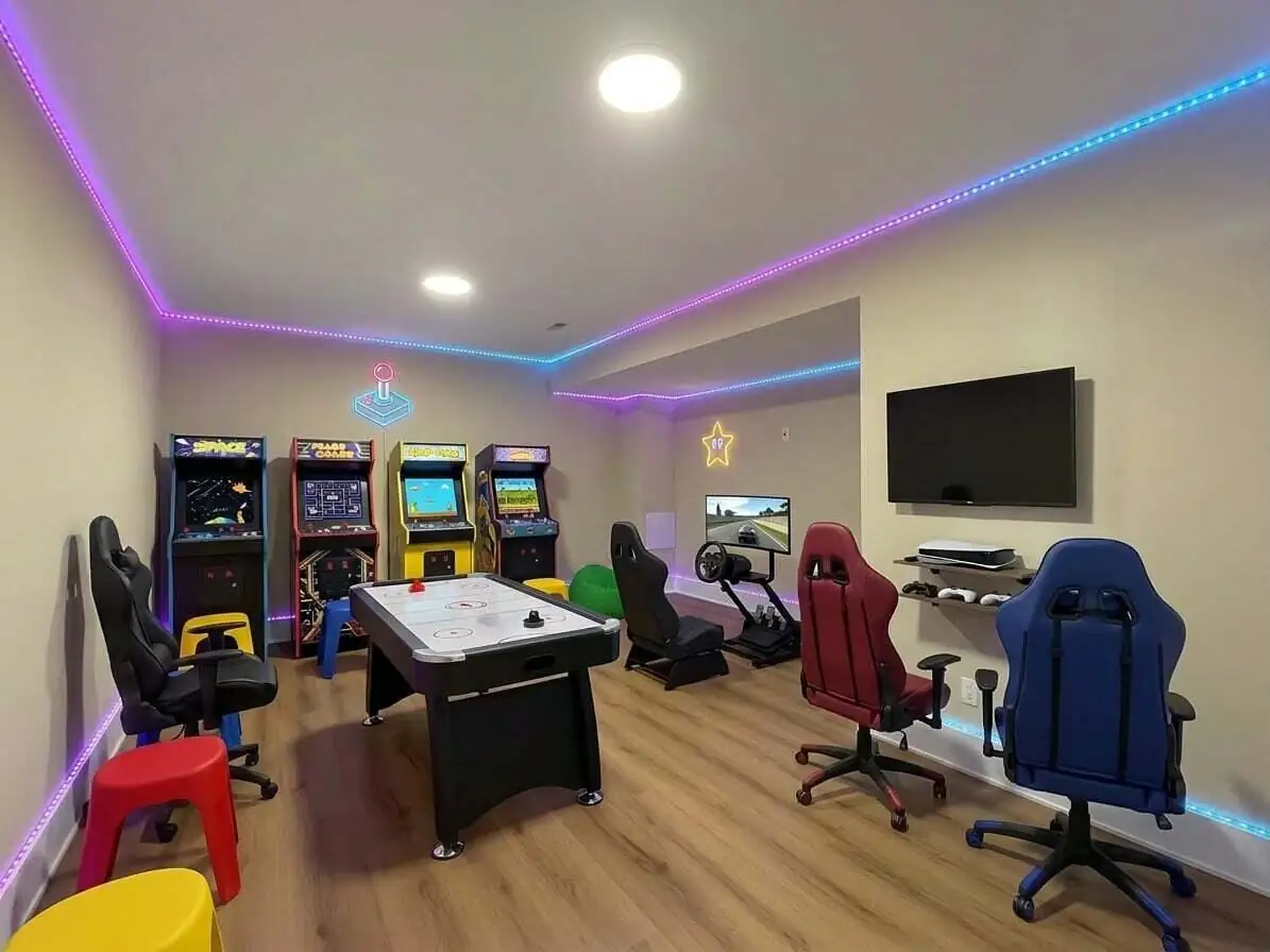Game room with matching gaming chairs set up around an air hockey table and racing simulator.