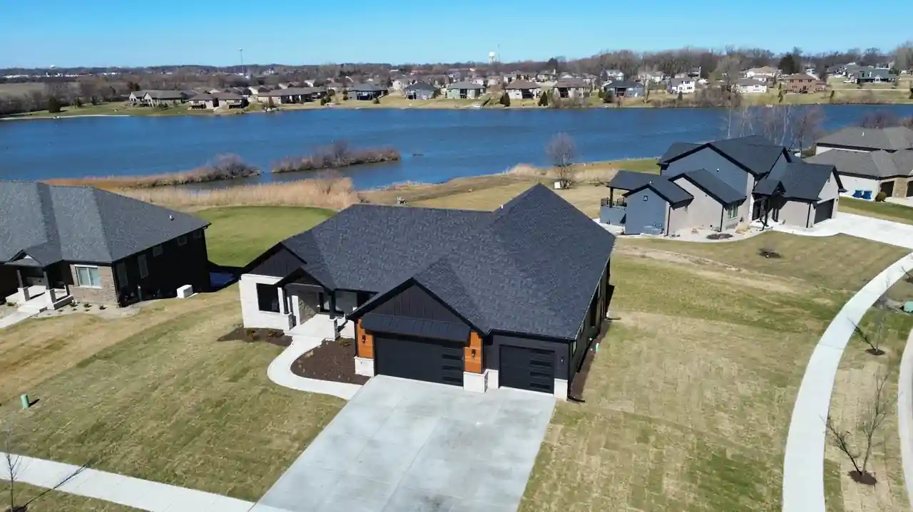 Daytime aerial view of the Lakeview New Construction home along its lakefront lot.