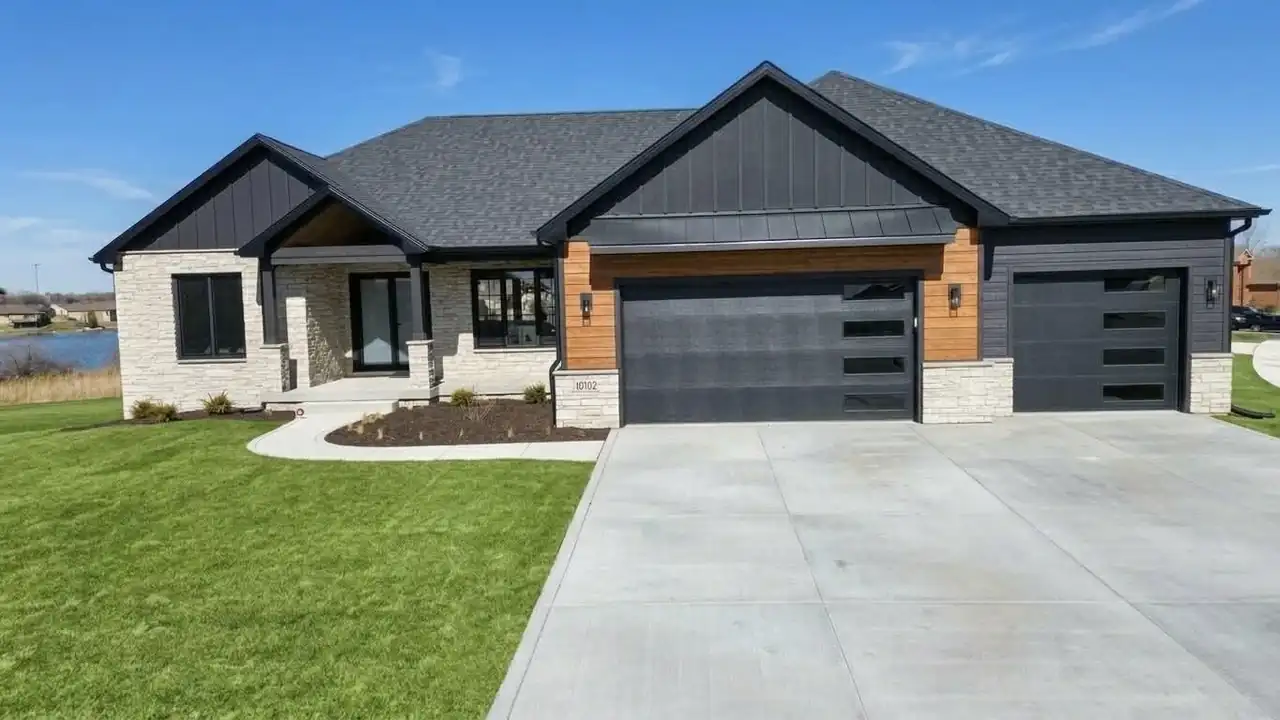 Ground-level view of the home's entry facade, showing stone piers and wood-accented garage bays.