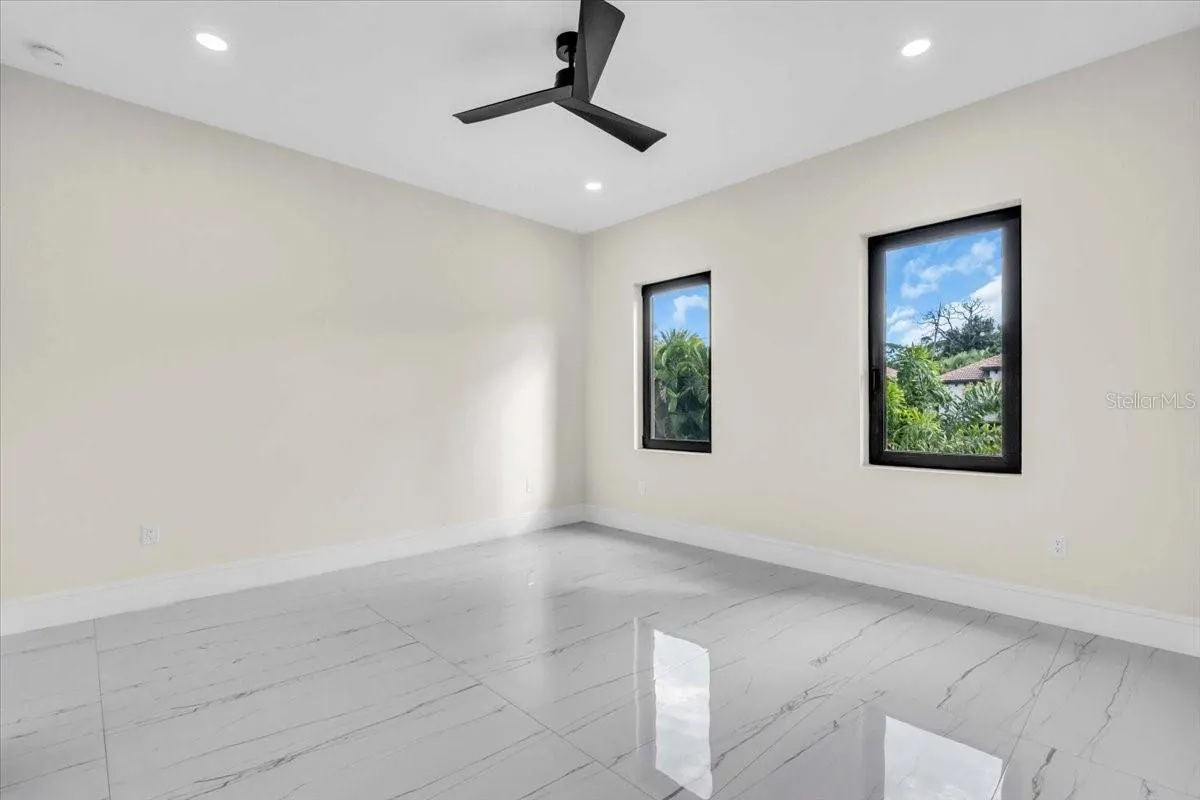 Unfurnished bedroom with two windows and a ceiling fan awaiting furnishings.