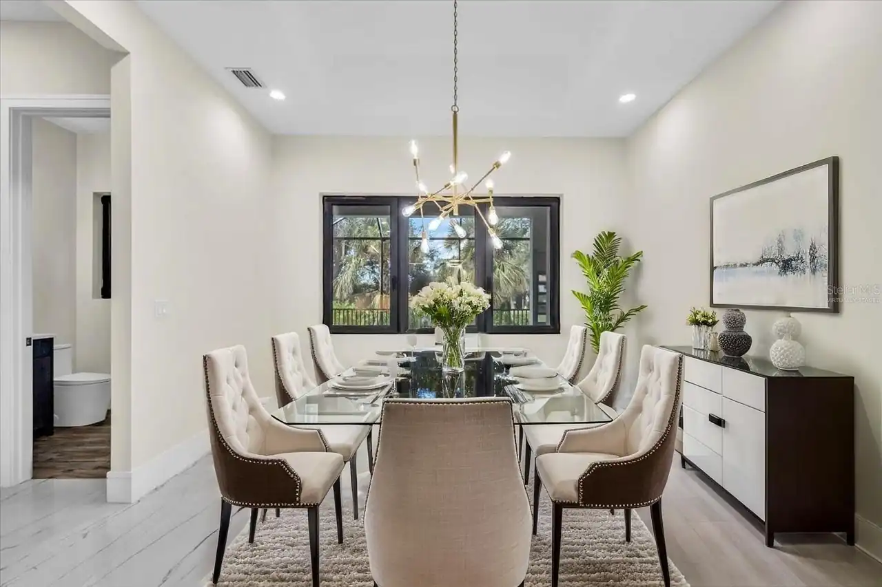 Dining room with a glass-top table, nailhead-trim chairs, and a two-tone sideboard.
