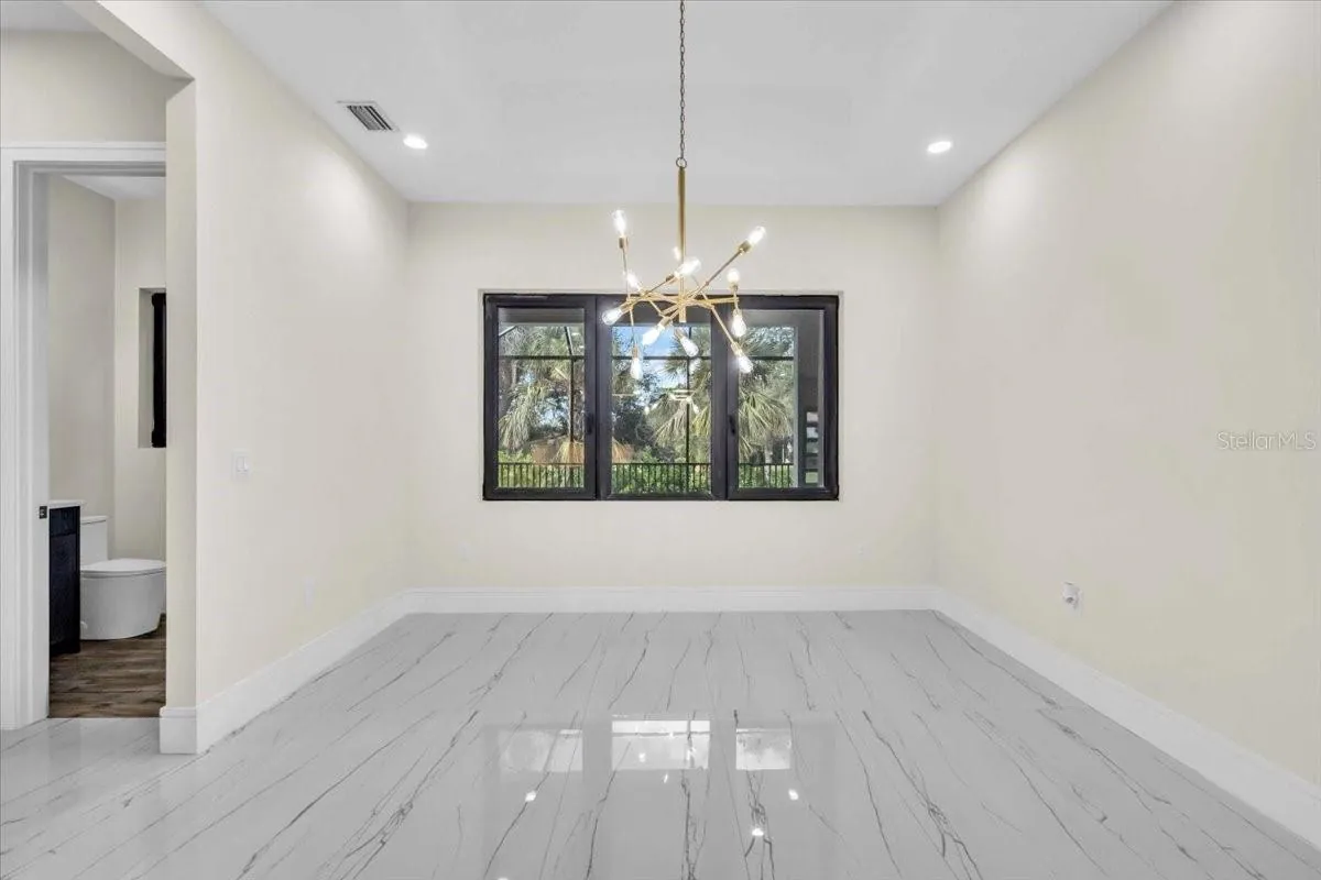 Unfurnished dining room with a brass chandelier and windows facing the balcony.