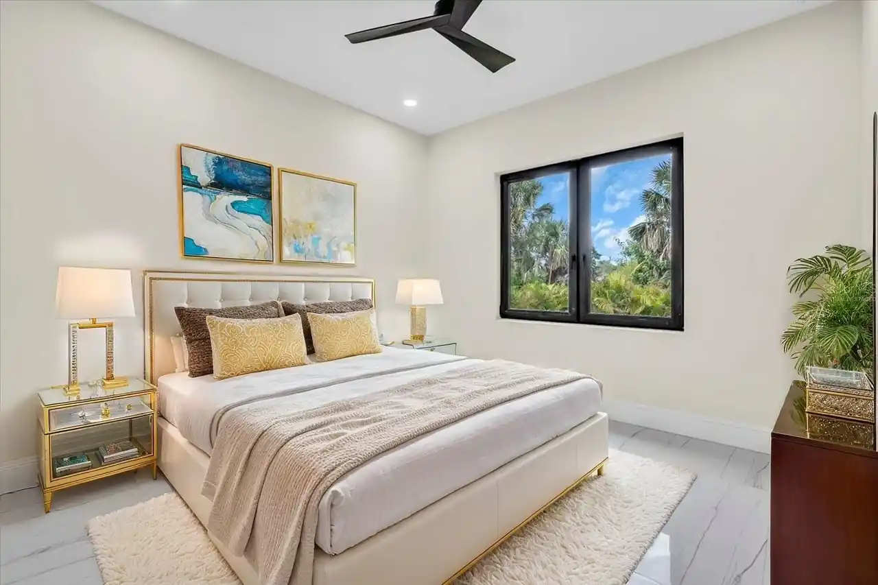 Bedroom with a cream tufted bed, gold-trimmed nightstands, and teal abstract art.