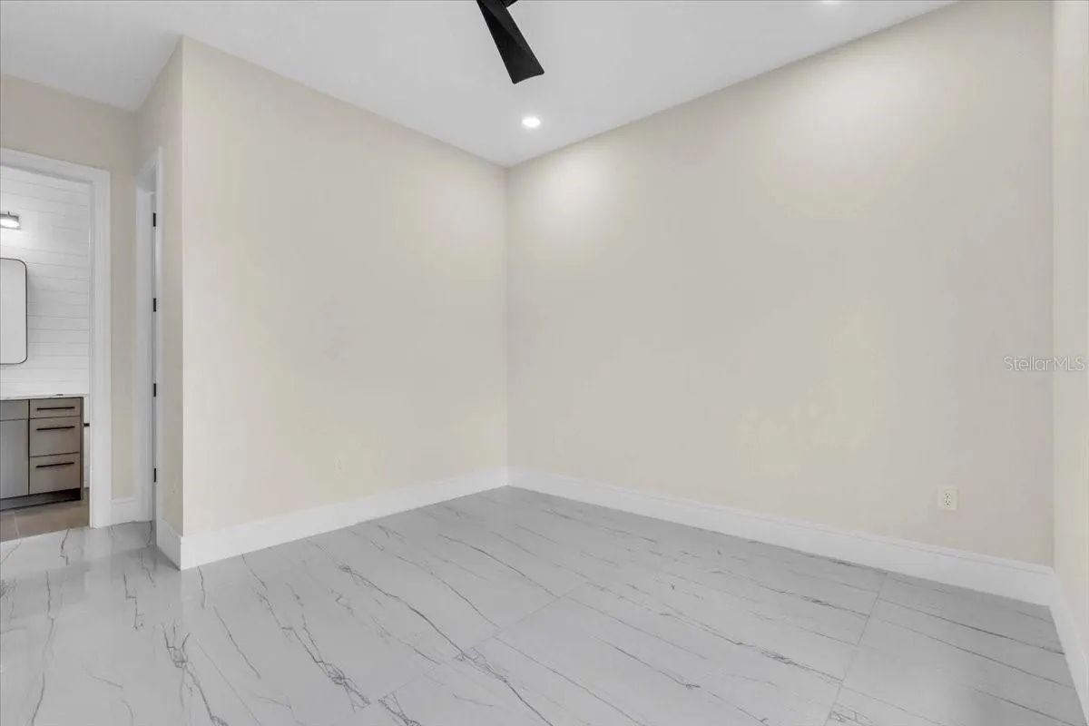 Empty bedroom with a single window, ceiling fan, and view toward the ensuite bath.