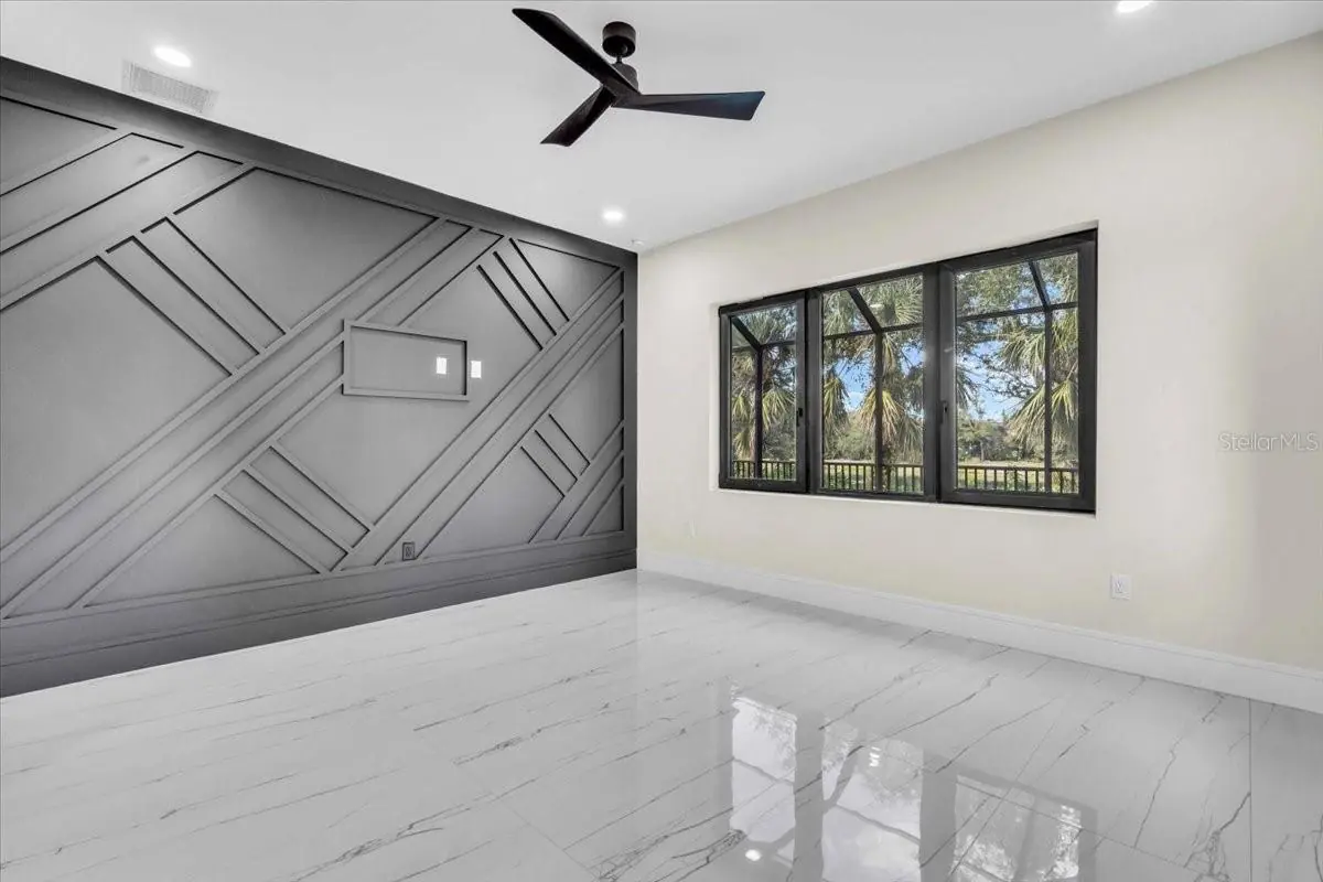 Unfurnished bedroom with a black diagonal-paneled accent wall and triple window.