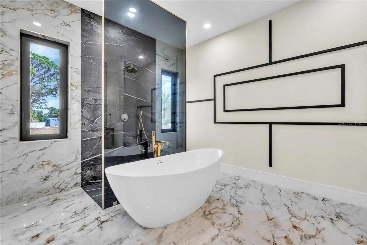 Primary bath with a dark stone shower, freestanding tub, and geometric wall art.