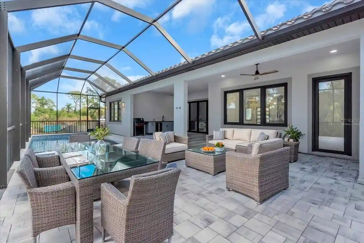 Screened lanai with wicker dining and lounge seating under a tiled roofline.
