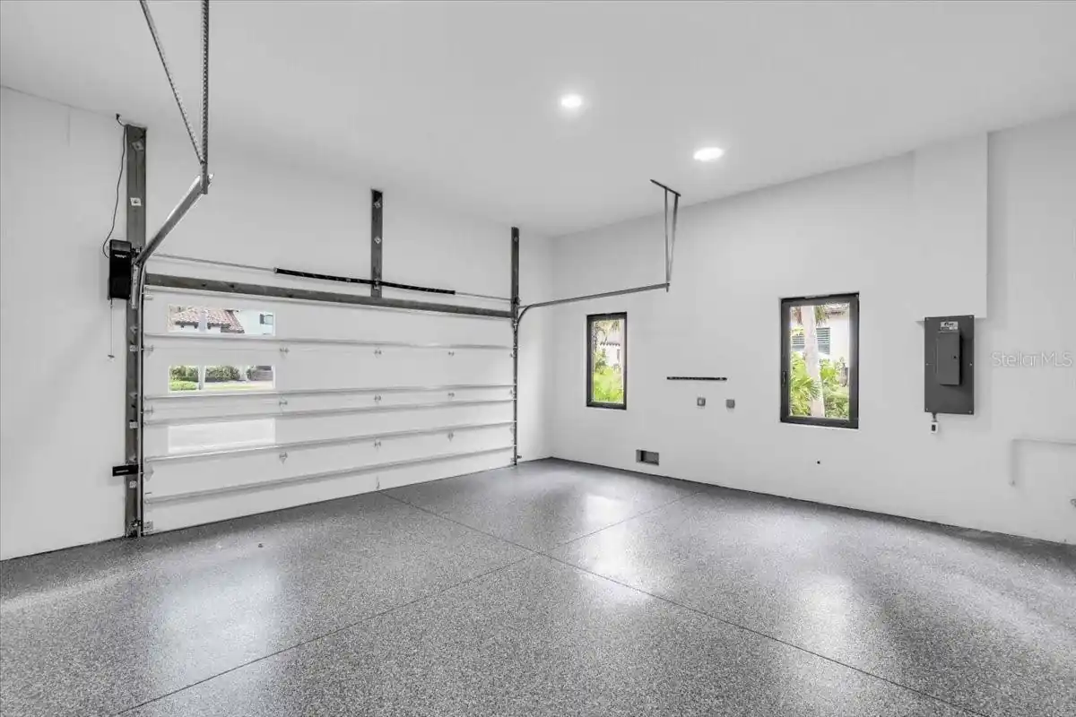 Garage interior with epoxy-flake flooring and an electrical panel.