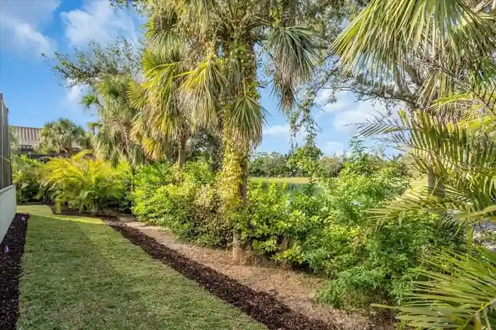 Landscaped path bordered by palms along the property's pond-view edge.