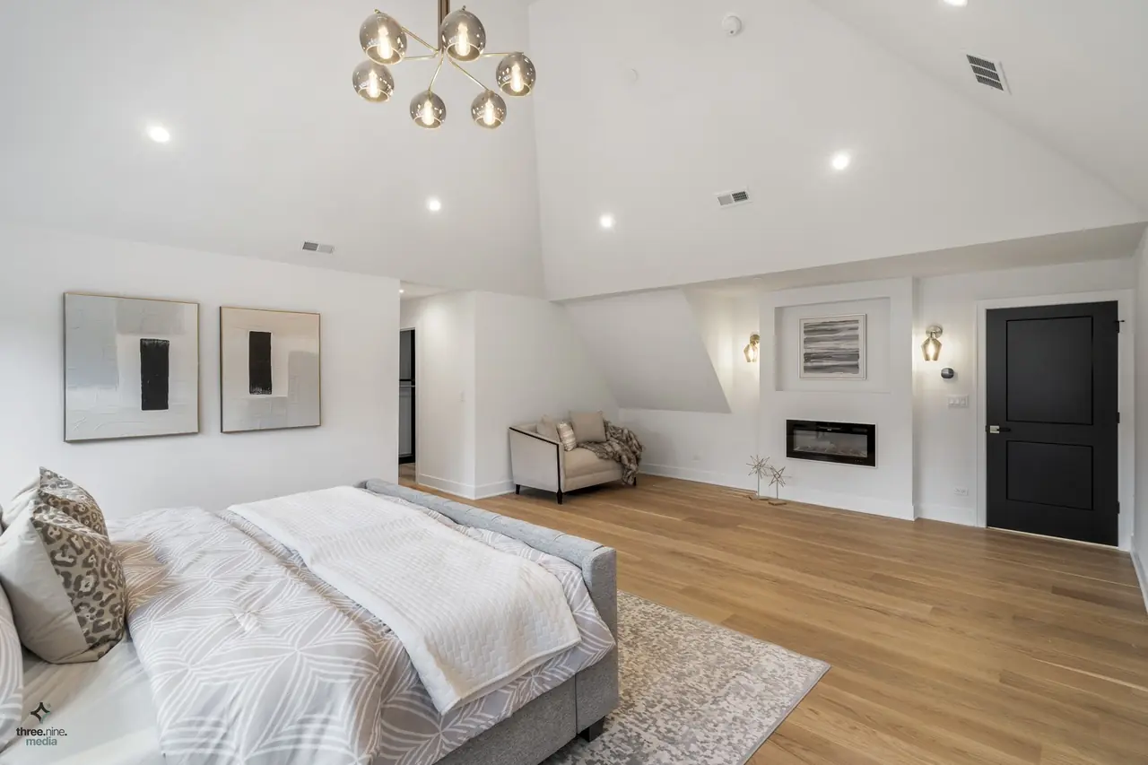 Primary bedroom with a black-framed fireplace wall and modern sconces