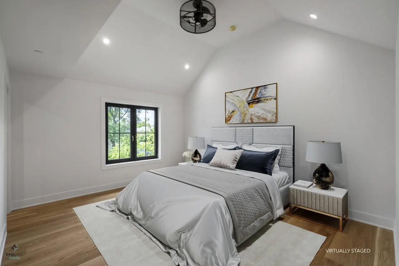 Virtually staged bedroom with a gray tufted headboard and black ceiling fan