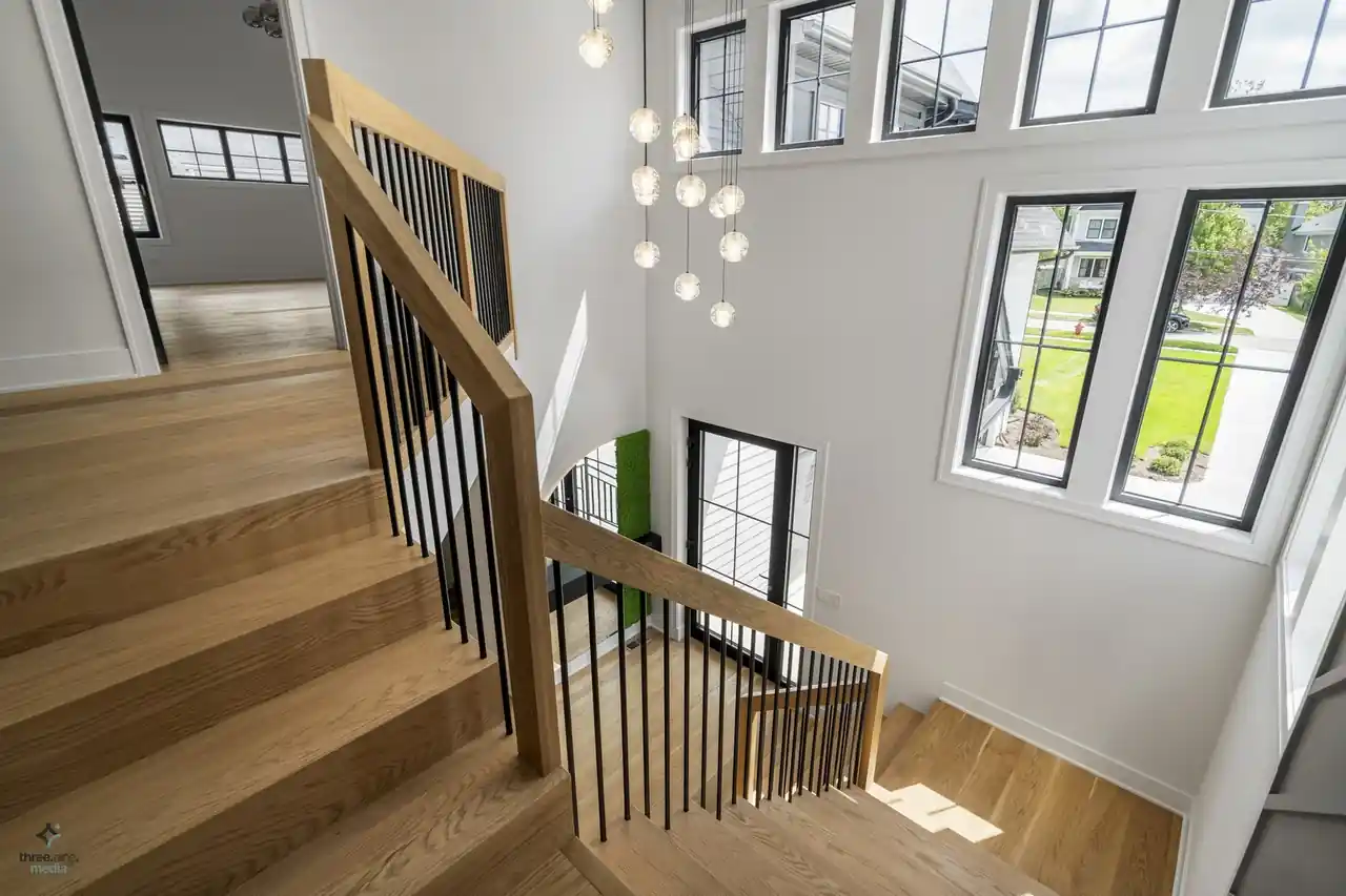 Overlook of the entry stairs with a bubble-glass chandelier and street-facing windows