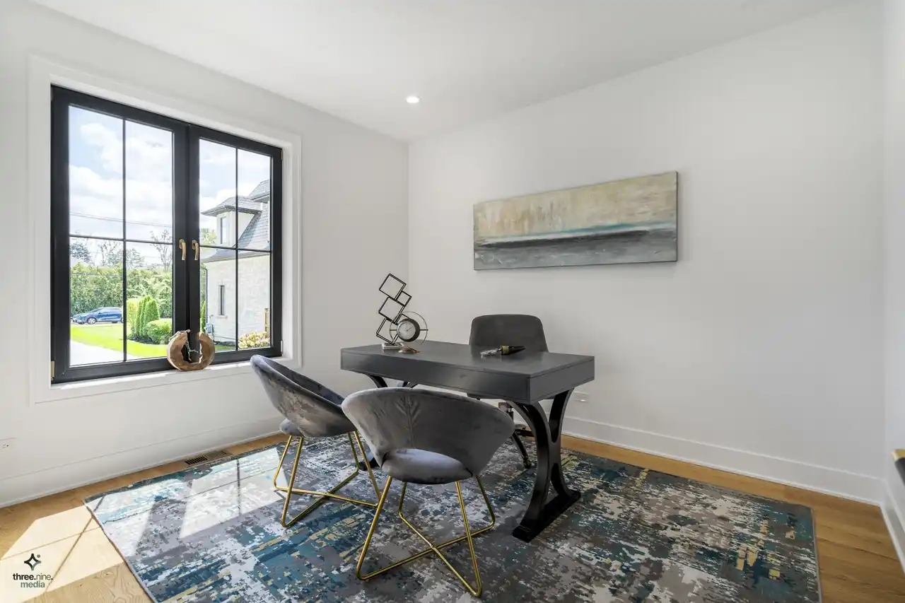 Home office with a sculptural black desk and a garden-view window