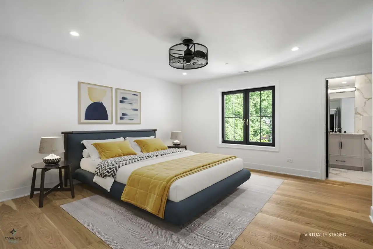 Virtually staged bedroom with navy and mustard bedding and an ensuite bath beyond