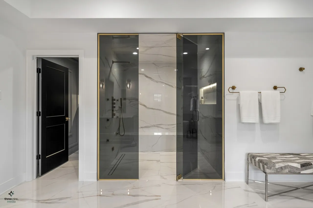 Glass-and-brass framed walk-in shower with a full marble surround