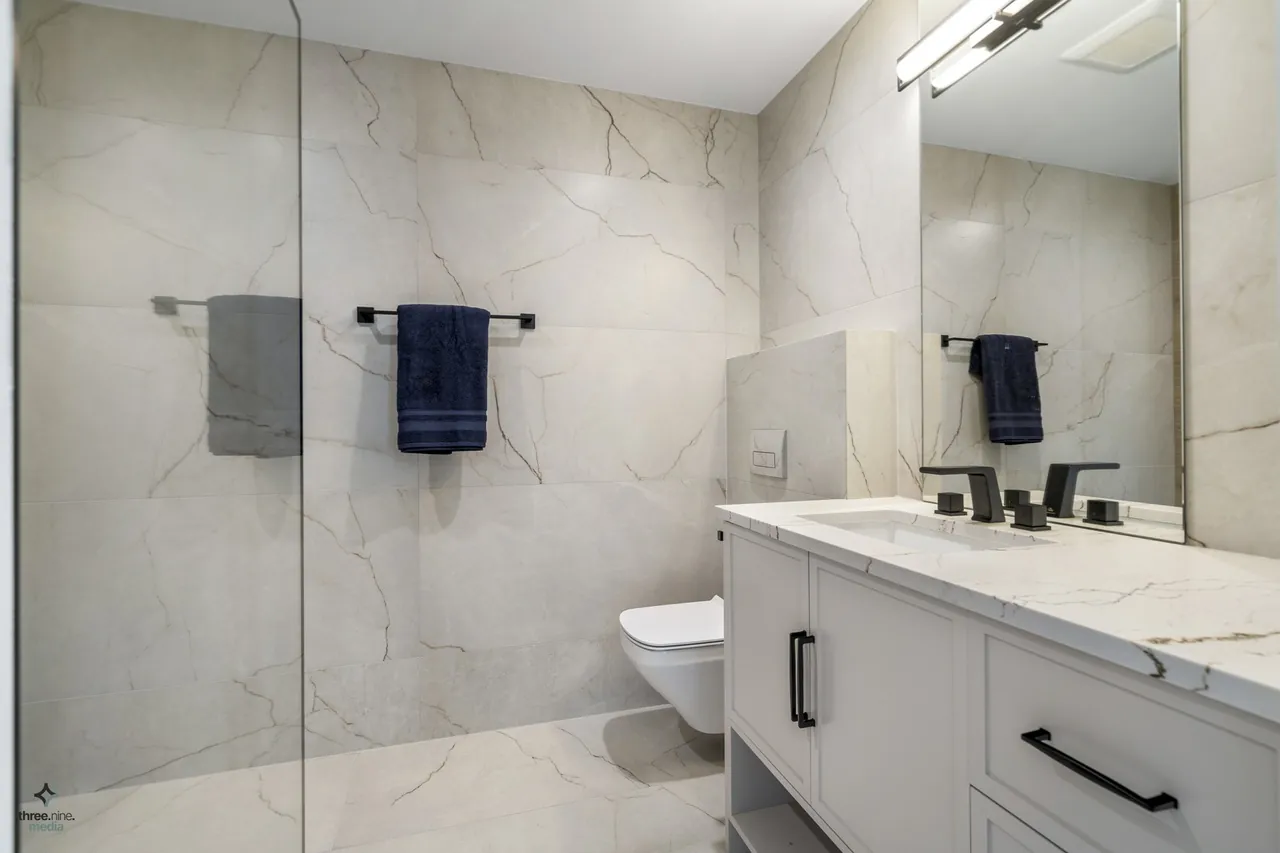 Guest bath with marble tile walls and a wall-mounted toilet