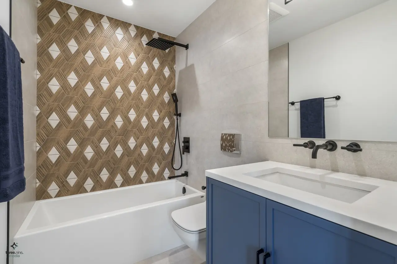 Tub-and-shower combo with a diamond-patterned accent tile wall and navy vanity