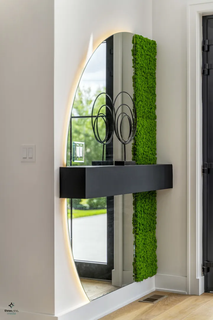 Entryway detail with a backlit arched mirror and moss wall accent