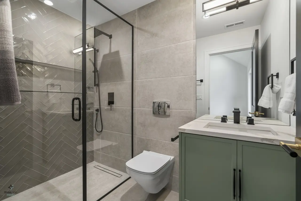 Bathroom with herringbone shower tile and sage green vanity cabinetry