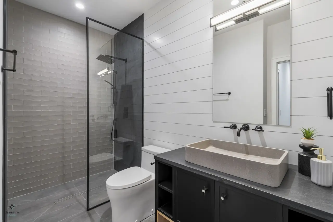 Bathroom with gray subway-tiled shower and a carved stone vessel sink