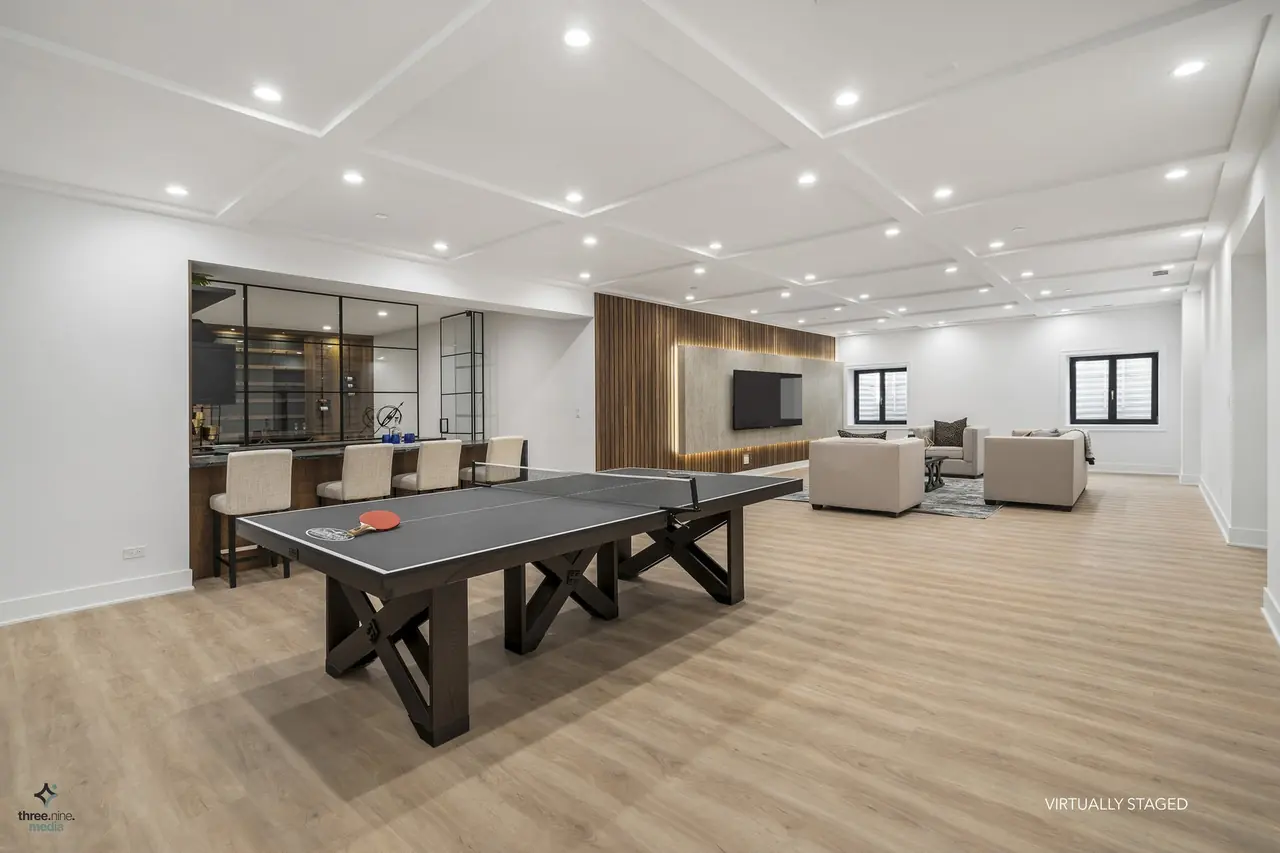 Basement game room with a ping pong table and wet bar in the background