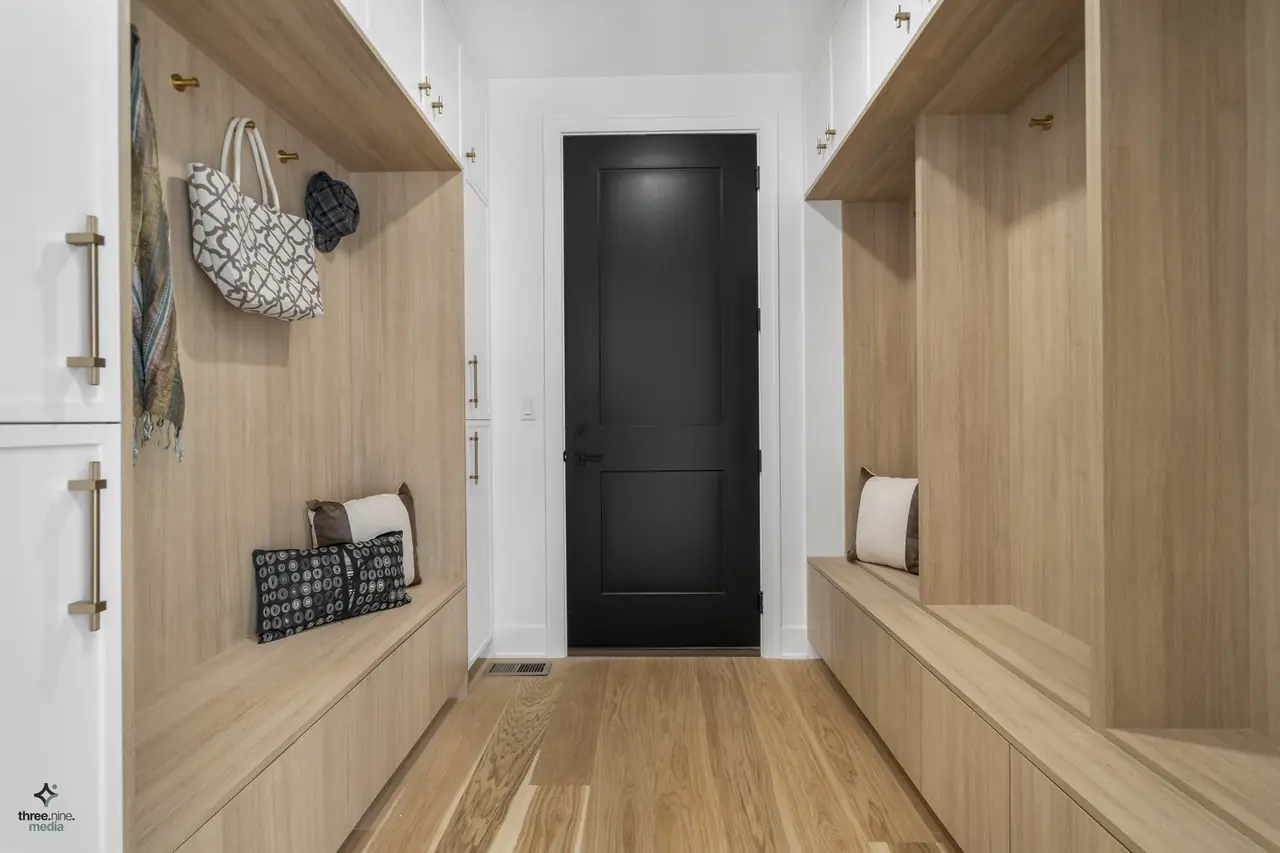 Mudroom with built-in wood lockers, bench seating, and brass hooks