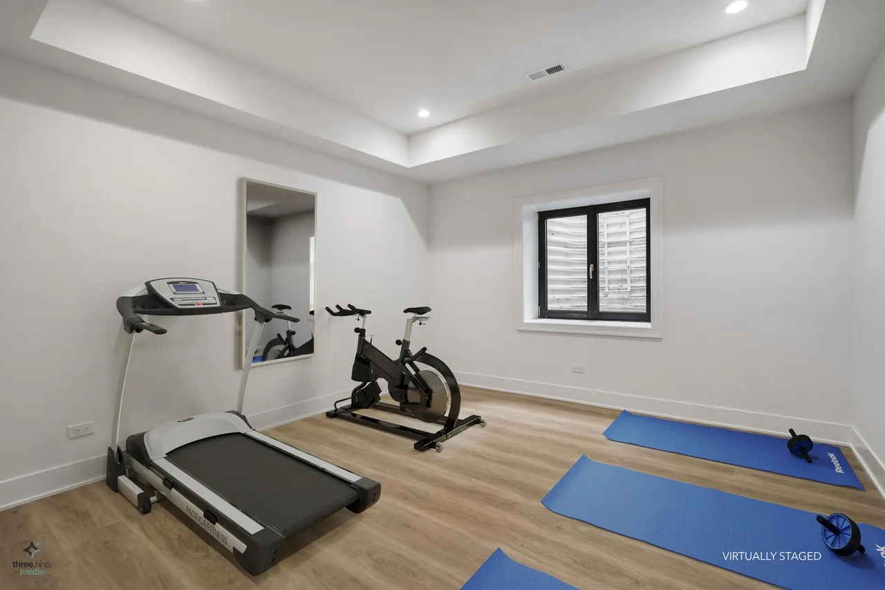 Virtually staged home gym with a treadmill, spin bike, and yoga mats