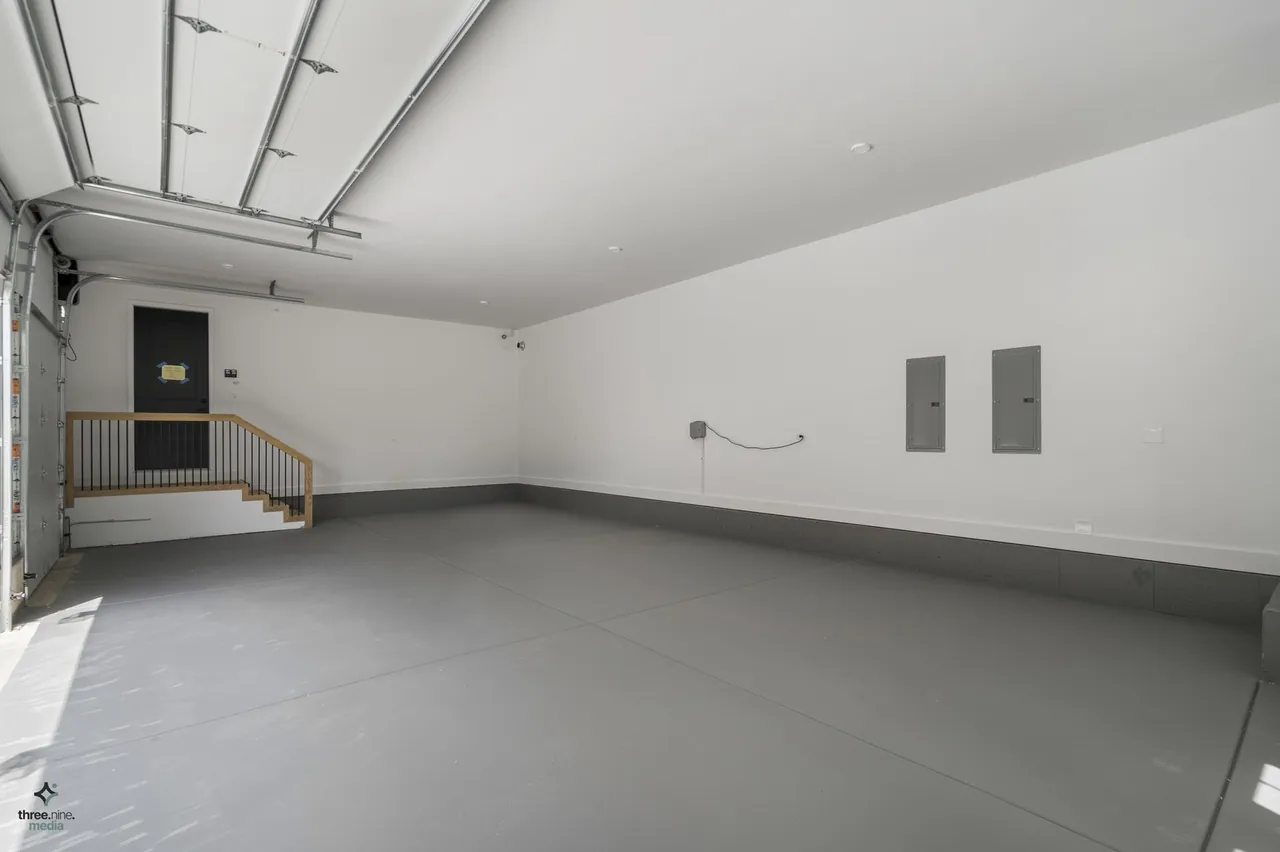 Unfinished garage space with epoxy flooring and a staircase to the main level