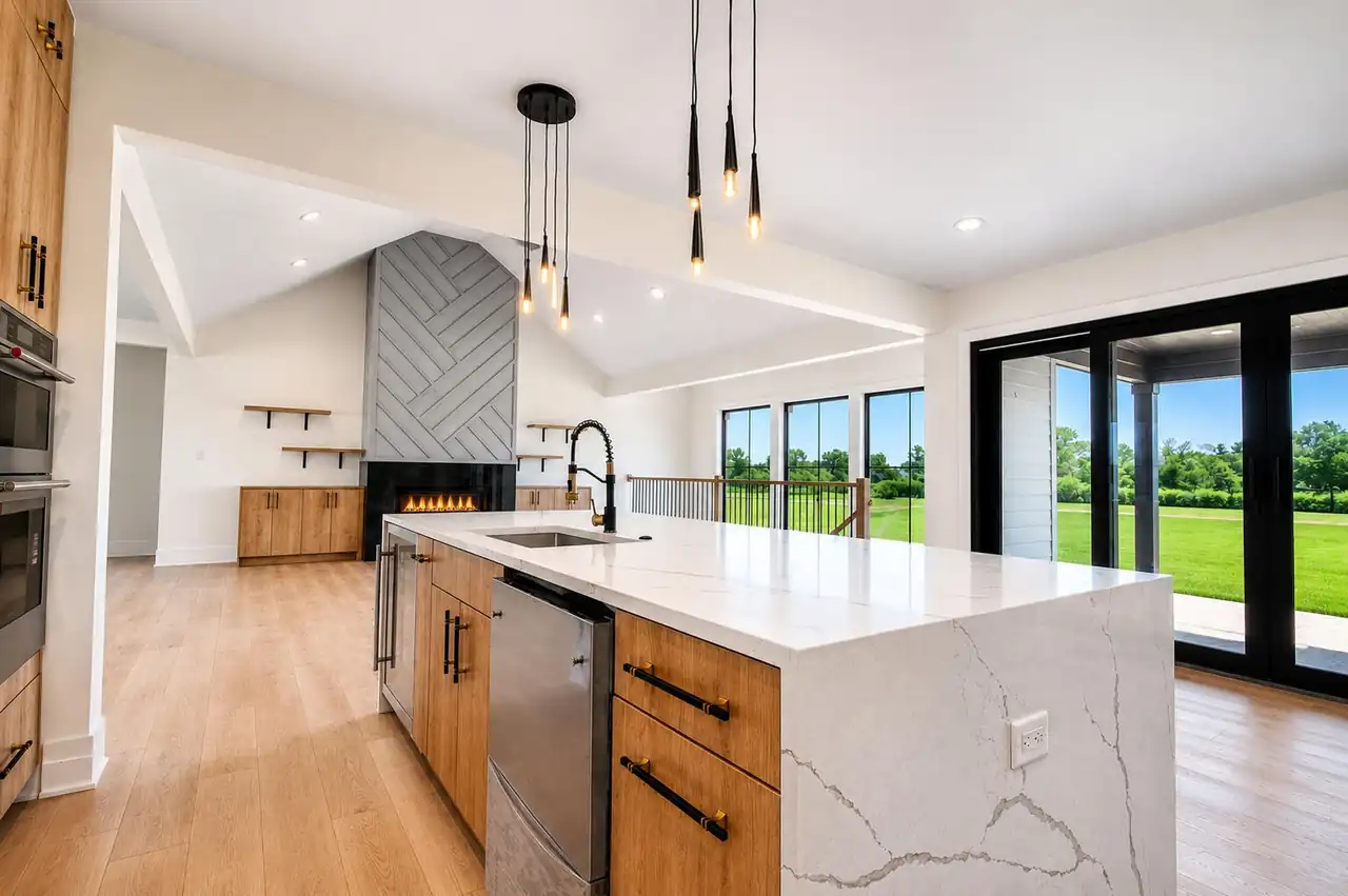 Kitchen island with pendant lighting opens to the great room fireplace and sliding glass doors to the patio.