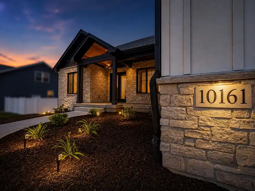 Twilight view of the covered entry with illuminated house number 10161 on the stone pillar at Springlake New Construction.