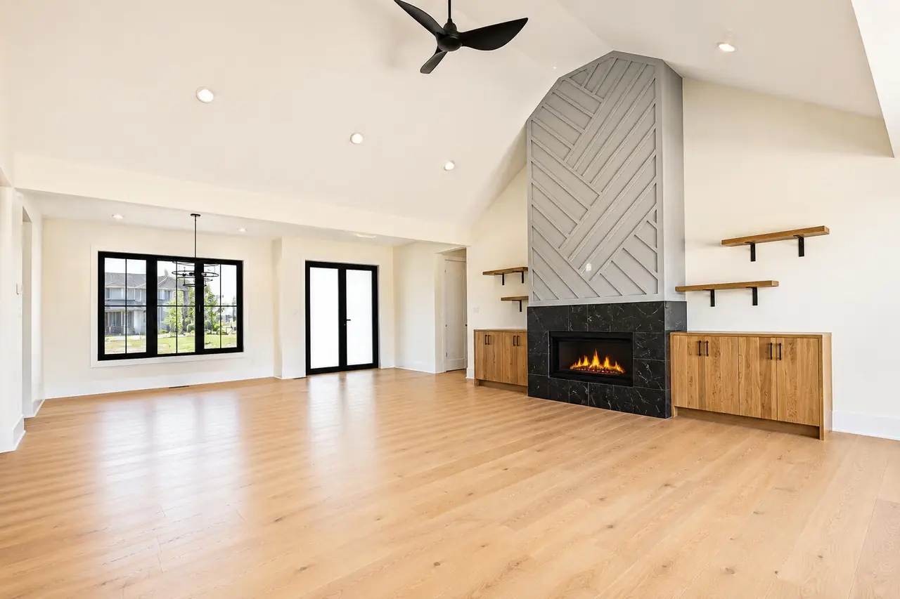 Vaulted great room with a black ceiling fan, wood floors, and a floor-to-ceiling herringbone tile fireplace surround.