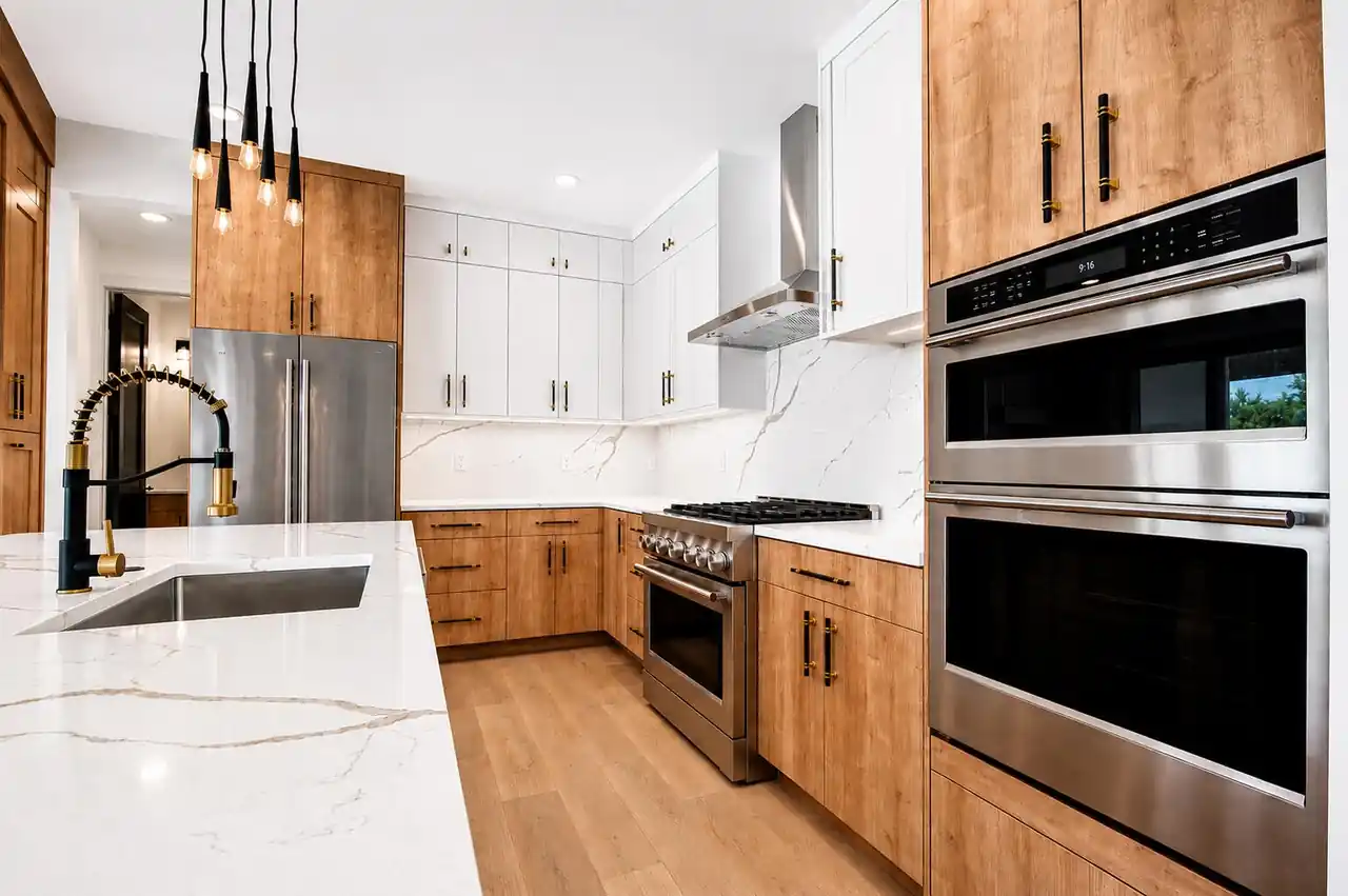 Kitchen with stacked stainless double wall ovens, a gooseneck faucet, and wood cabinetry with brass hardware.