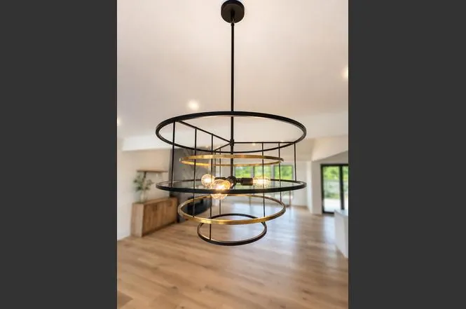 Layered black and brass ring pendant light fixture hanging above the dining area's wood floors.