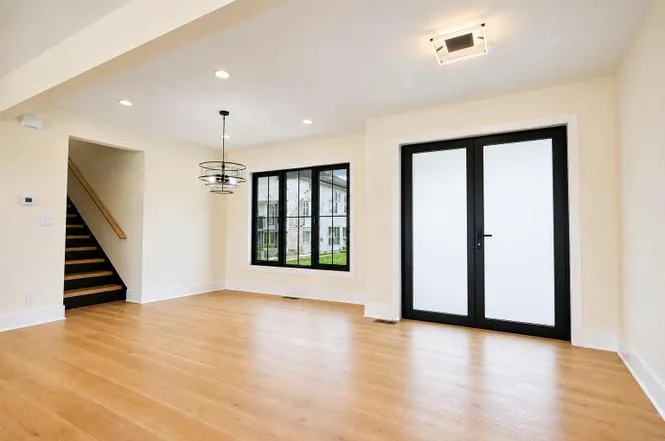 Foyer with black double front doors, a wood staircase to the lower level, and views of the neighborhood.