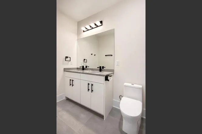 Secondary bathroom with a dual-sink vanity, gray countertop, and matte black hardware.