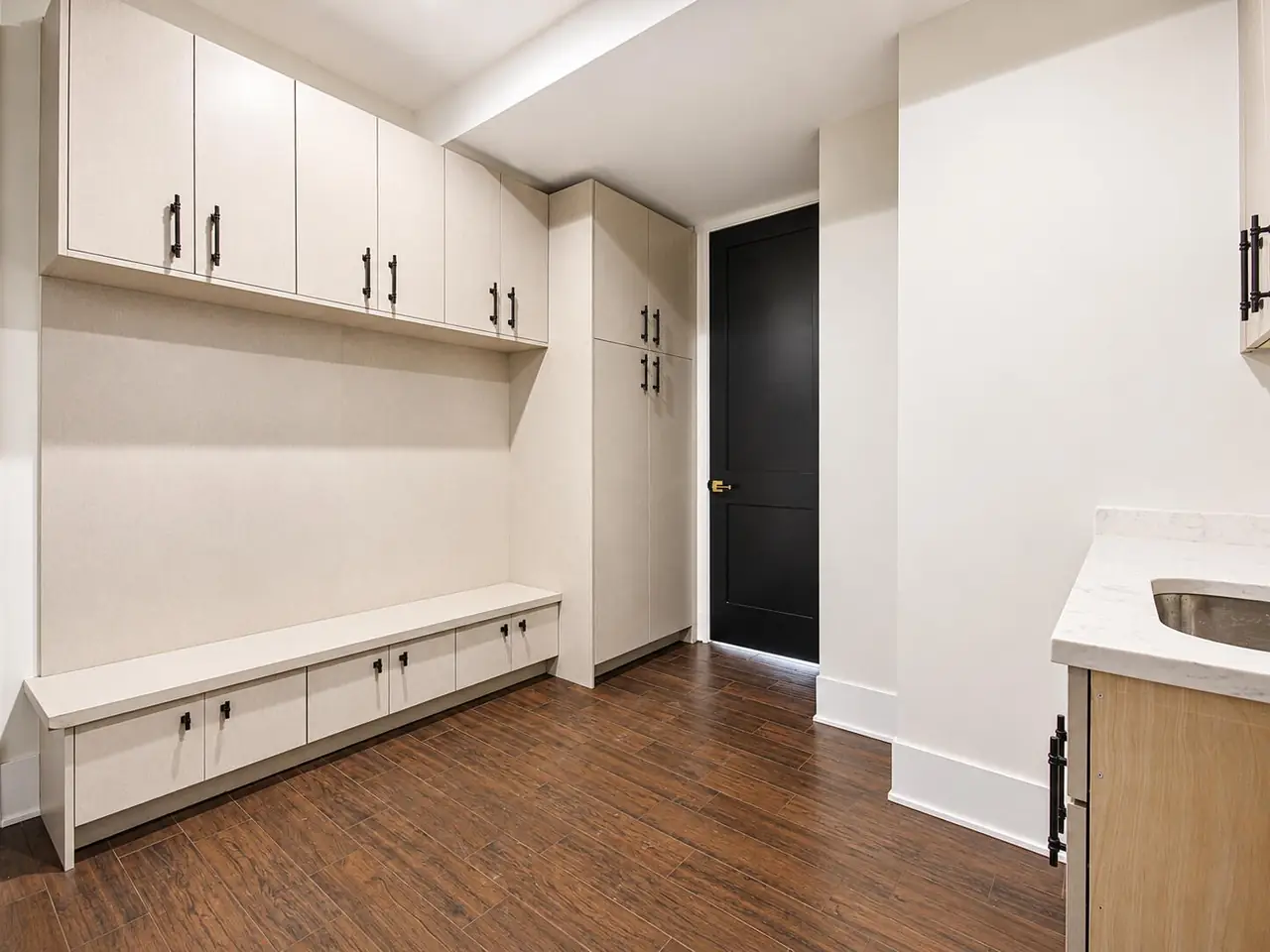 Mudroom with white built-in cabinetry, a storage bench, and wood-look tile flooring.