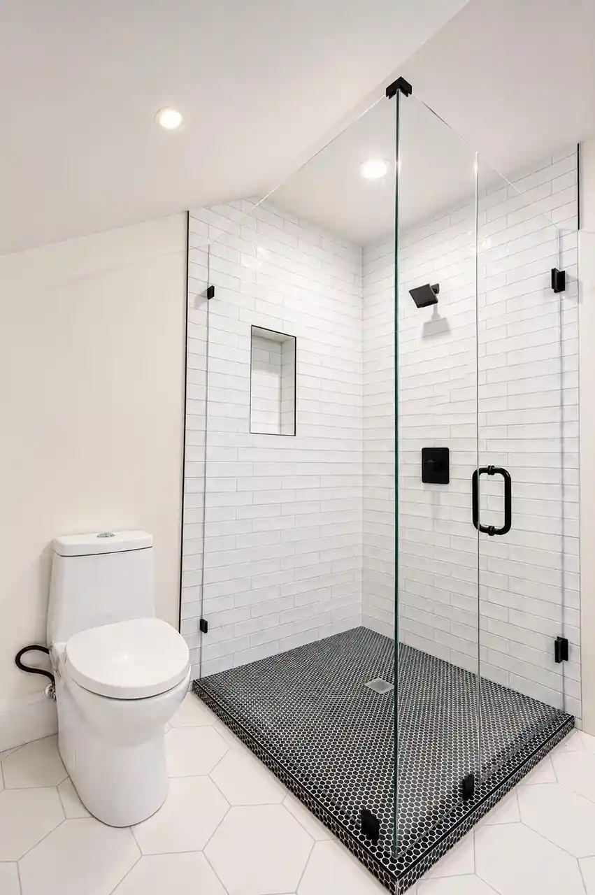 Bathroom with a glass shower enclosure, white subway tile, and a black hexagon-tile shower floor.