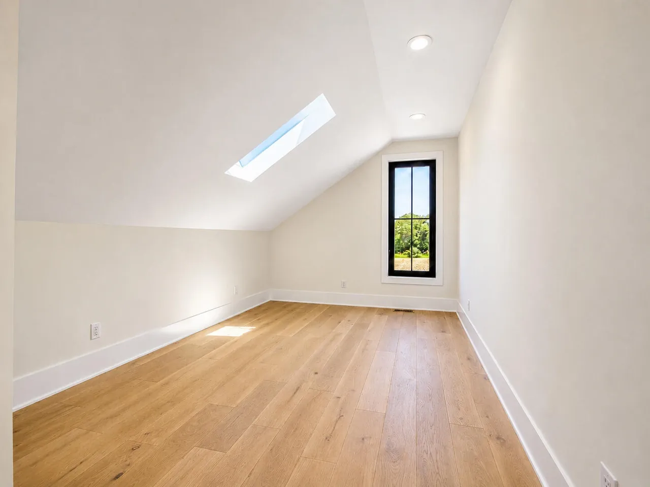 Unfinished upper bonus room with a skylight and black-framed window, ready for future finishing.