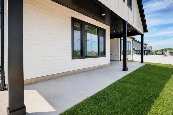 Covered back porch corner view with black-framed windows and a look toward the neighboring fence line.