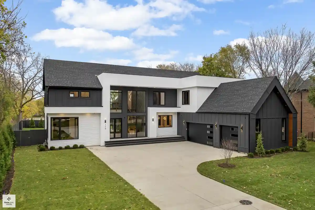 Daytime front exterior of the two-story modern farmhouse with black garage doors and circular driveway