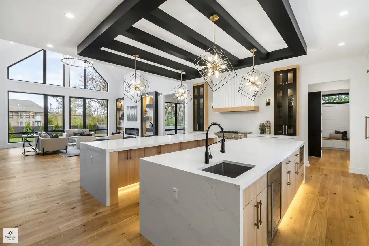 Kitchen island sink with black faucet, overlooking the vaulted great room beyond