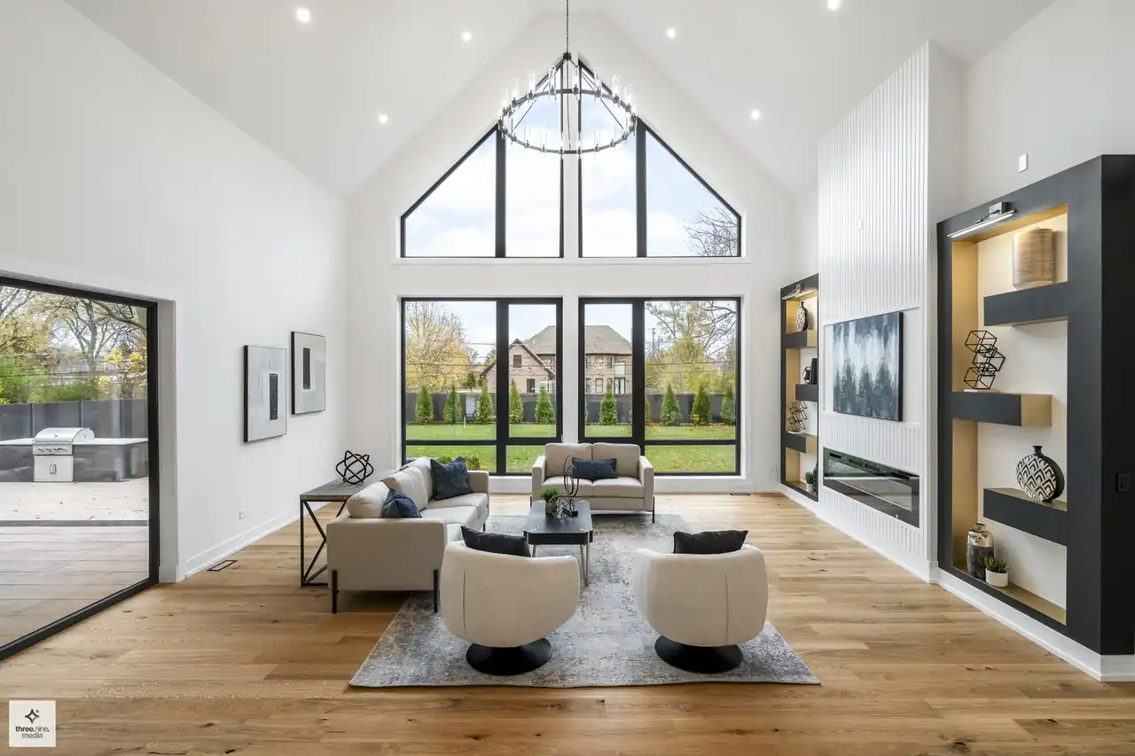 Vaulted great room with peaked window wall, ring chandelier, and built-in display shelving