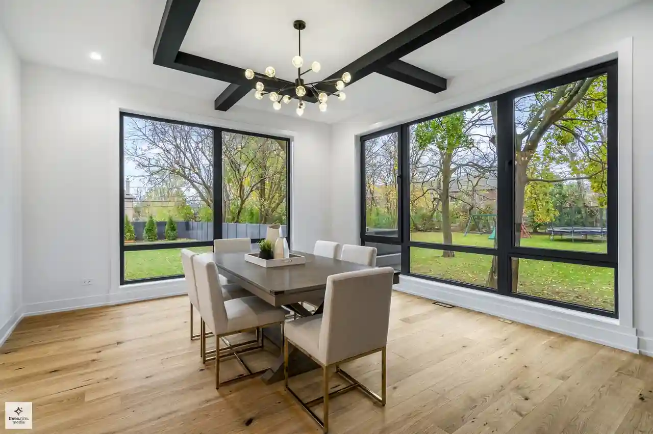 Dining nook with floor-to-ceiling black-framed windows overlooking the backyard