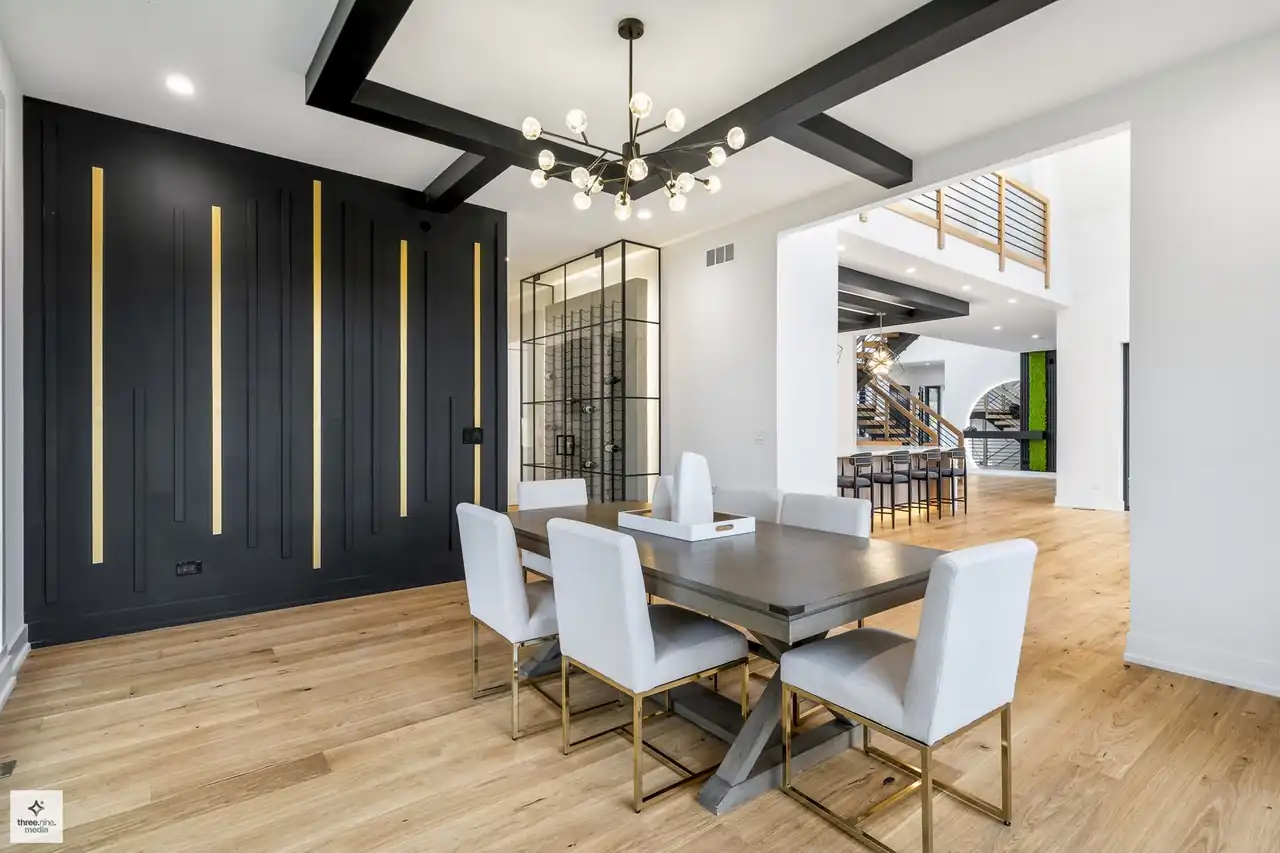 Dining room with a black-and-gold accent wall and glass wine display beyond