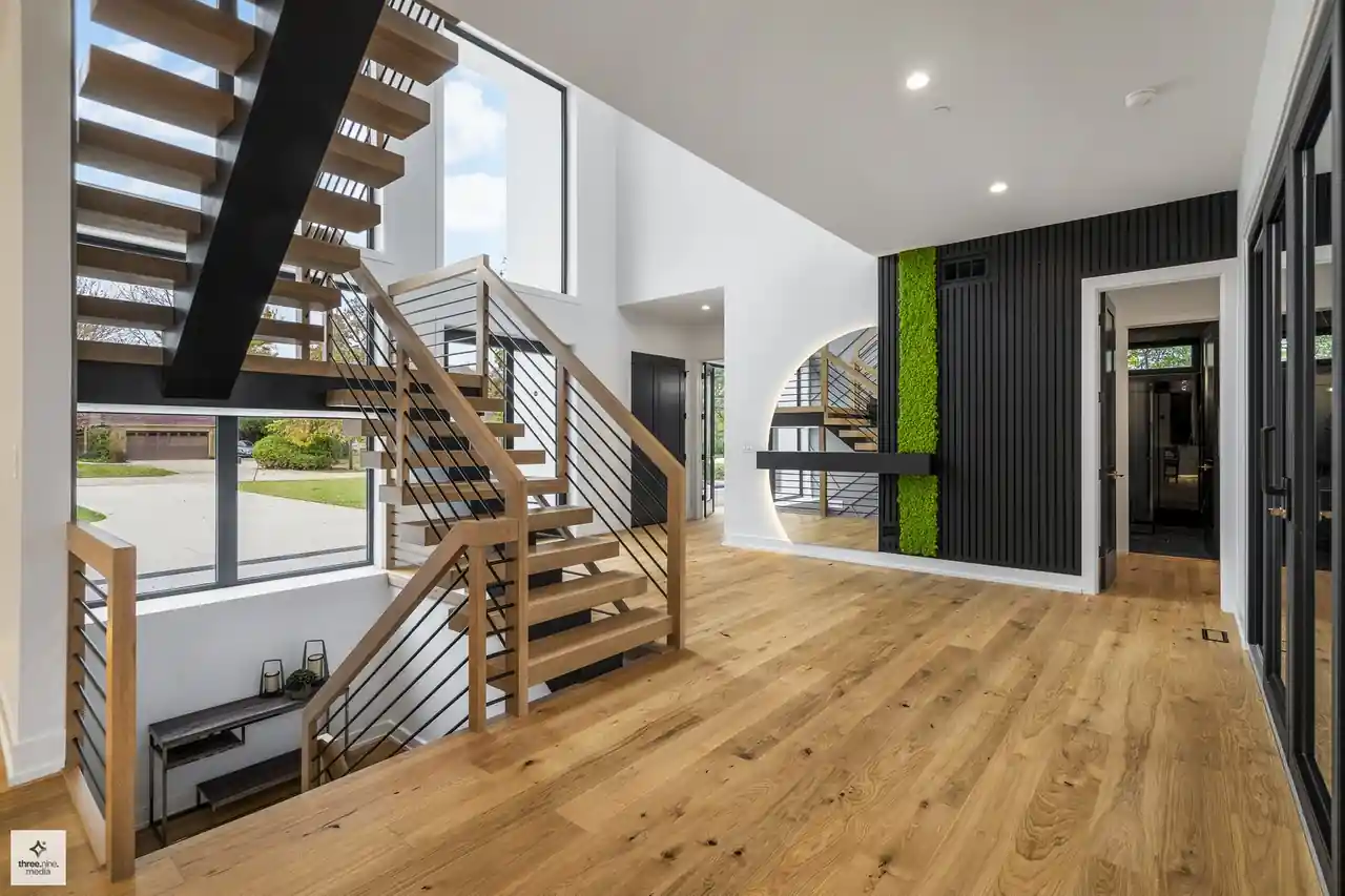 Entry foyer with open-tread staircase, wood railings, and a living moss accent wall