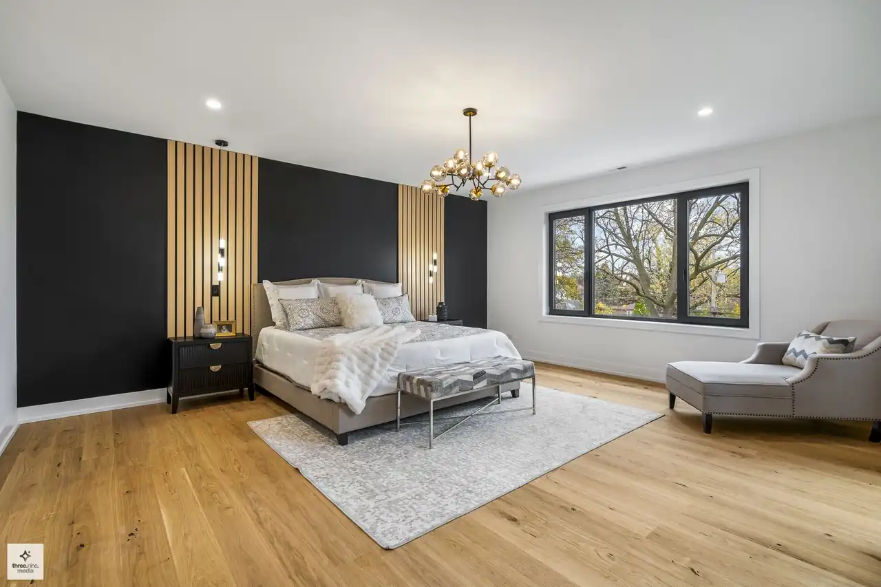 Primary bedroom with a black-and-wood slat accent wall and drum chandelier