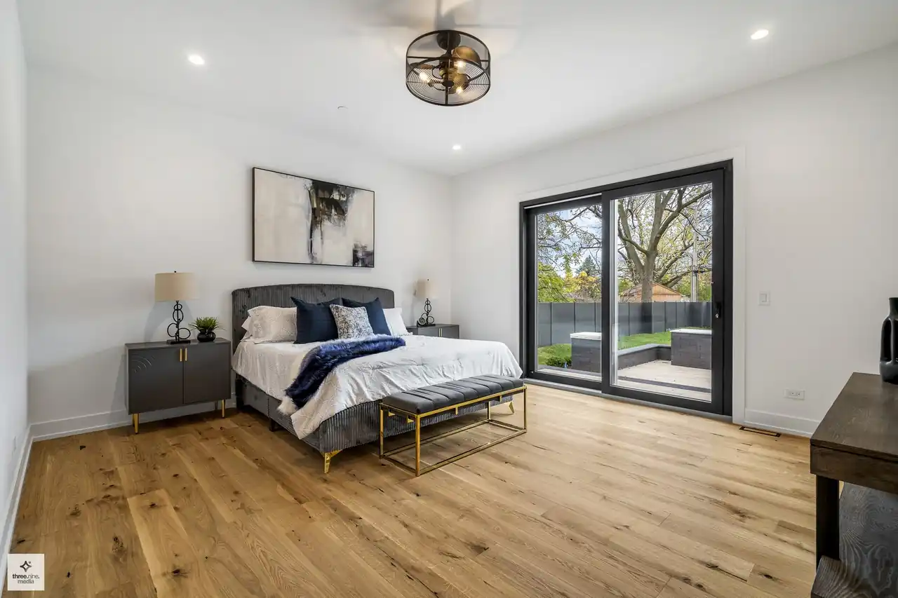 Secondary bedroom with a caged ceiling fan and sliding doors to the backyard patio